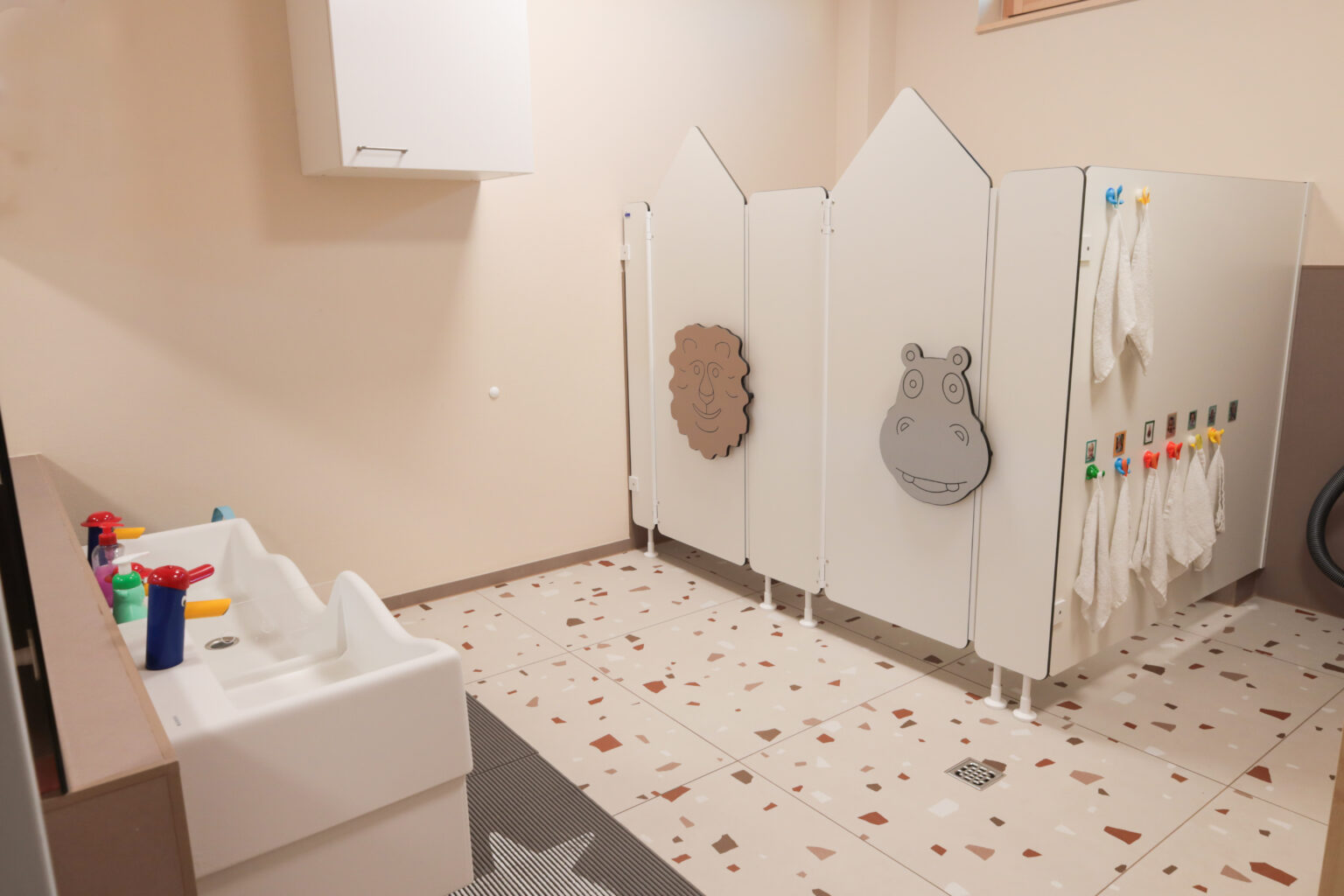 Das Badezimmer der Kindergroßtagespflege ist kindgerecht ausgestatt. Es gibt niedrige Waschbecke, Toilettenkabinen und einen Wickeltisch.