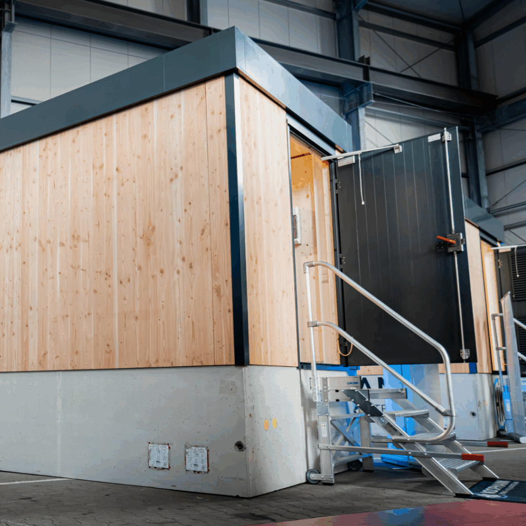 Netzstation in Holzbauweise mit Stiegenaufgangund geöffneter Tür in der Halle